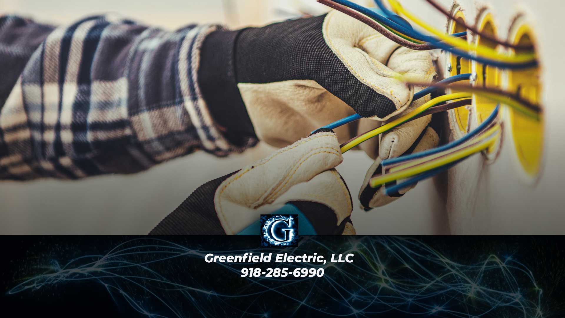  Closeup of a person wearing gloves doing electrical trim-out work with Greenfield Electric, LLC logo